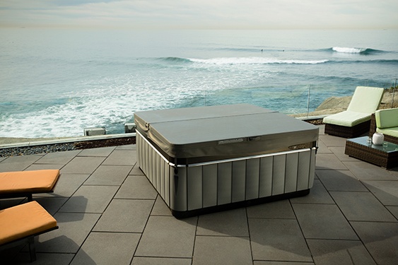 A Utopia Spa perched on a cliffside patio with the ocean in the background demonstrates the energy efficiency of the best quality hot tub covers
