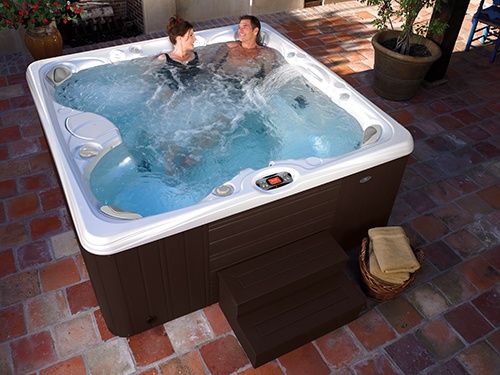 a couple relaxes in a paradise salina jacuzzi on a beautifully designed backyard patio