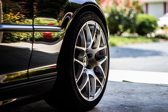 an image of a tire on a black car is used to support a discussion comparing auto maintenance to hot tub maintenance and comparing the benefits